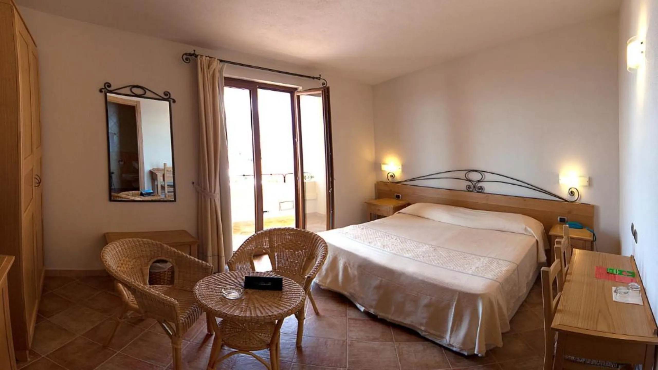 Interno della Suite dell'Hotel Villa Gustui Maris a Cala Gonone con letto matrimoniale e salotto in vimini.