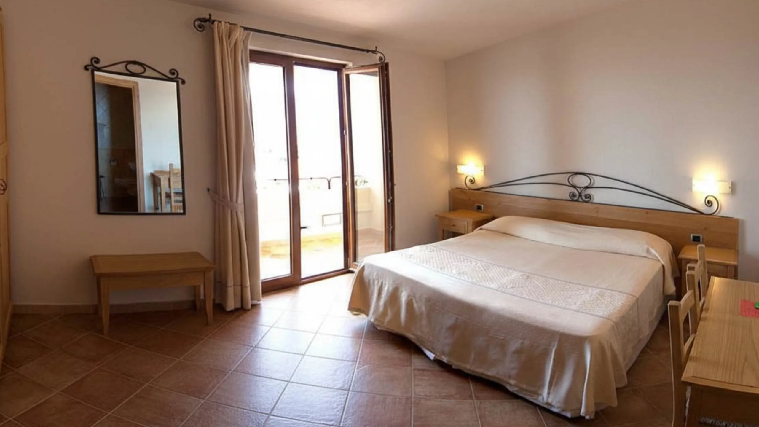 Suite matrimoniale spaziosa dell'Hotel Villa Gustui Maris con arredi tipici e balcone privato a Cala Gonone.